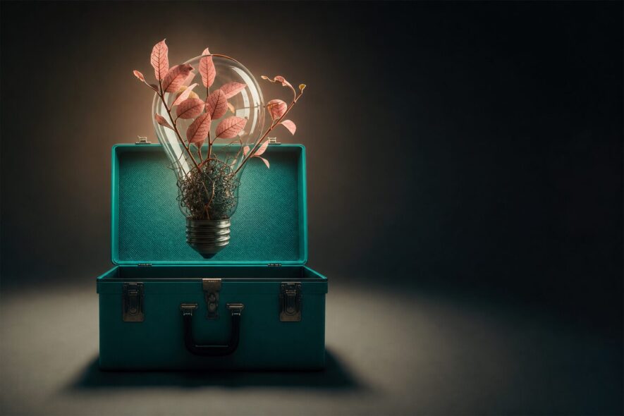 A toolbox with a lightbulb suspended over it with foliage flowing from inside it