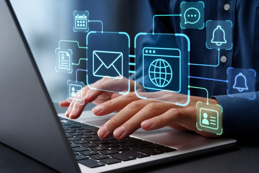 A close-up of hands typing on a laptop with glowing icons floating above them
