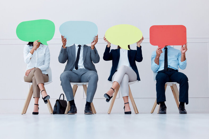 Row of people sitting holding signs over their faces to indicate their different brand voices.