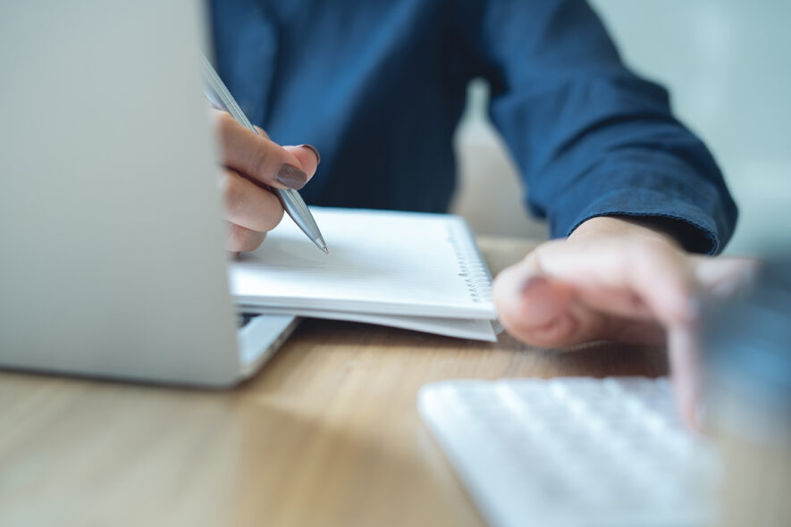 Close up person using calculator and laptop to build a quote