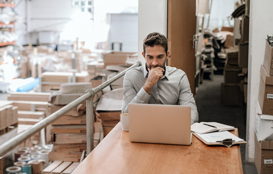 Manager working online while sitting in a warehouse office