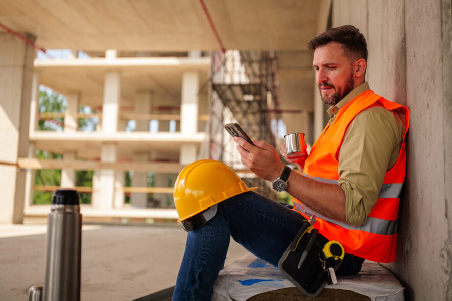 Tradie taking a coffee break, checking their phone.
